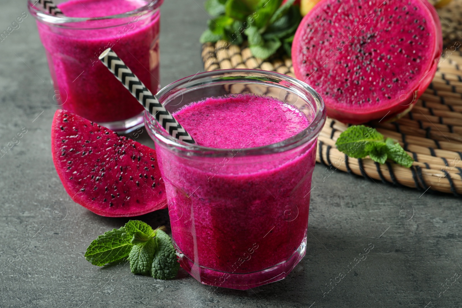 Photo of Delicious pitahaya smoothie, fruits and fresh mint on grey table