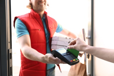 Photo of Woman paying for food delivery with credit card at door, closeup
