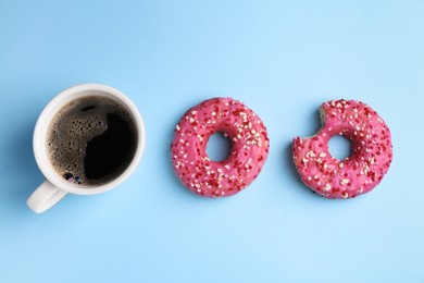 Tasty donuts and cup of coffee on light blue background, flat lay