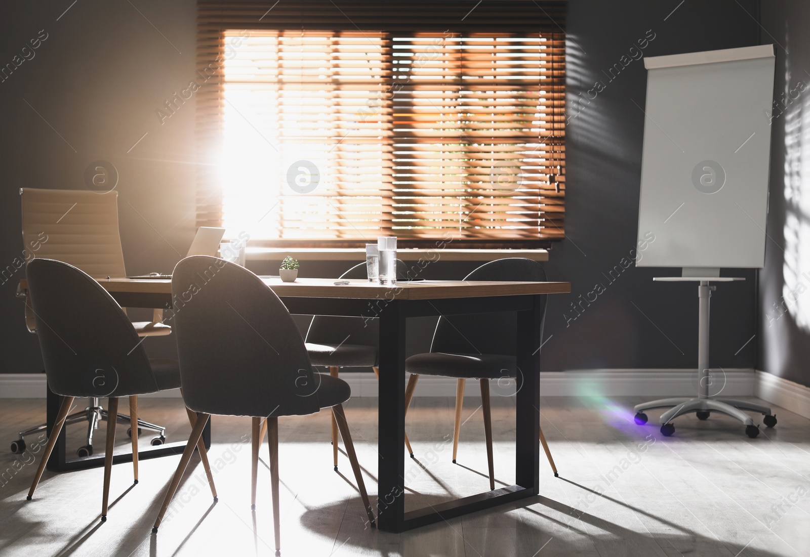 Photo of Stylish office interior with wooden table and flipchart