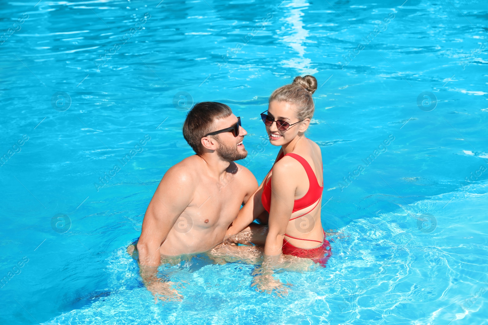 Photo of Happy young couple relaxing in swimming pool at resort