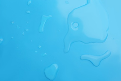 Photo of Drops of spilled water on light blue background, top view