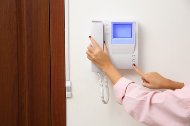 Photo of African-American woman pressing button on intercom panel indoors, closeup