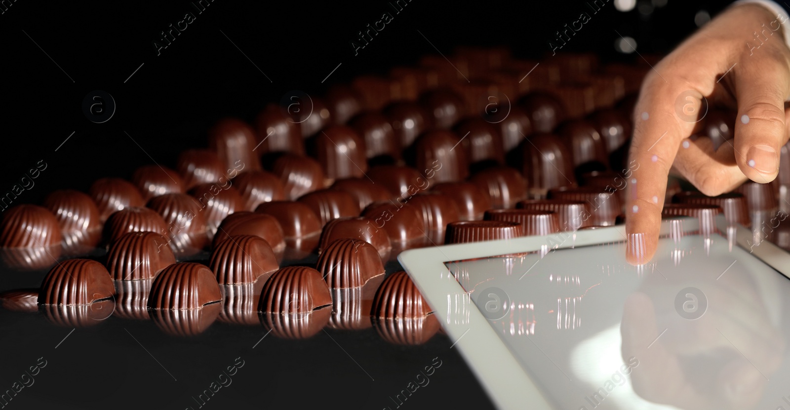 Image of Production line of chocolate candies. Man working with tablet, closeup. Banner design