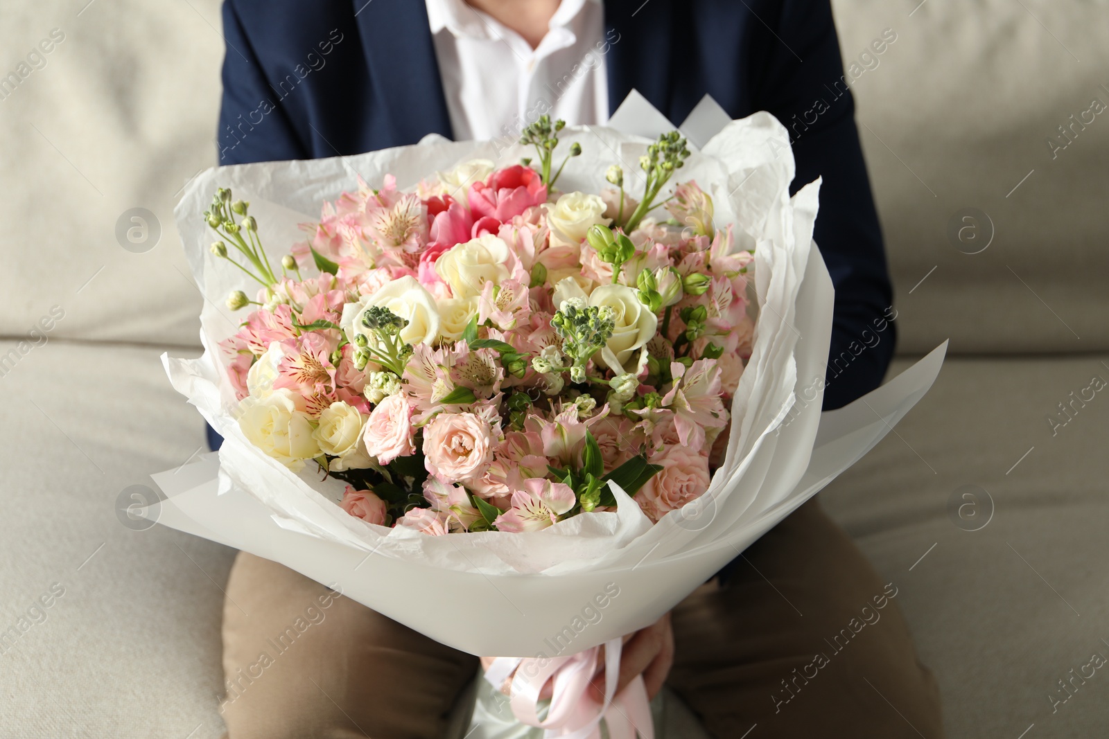 Photo of Man with beautiful bouquet of flowers on sofa indoors, closeup