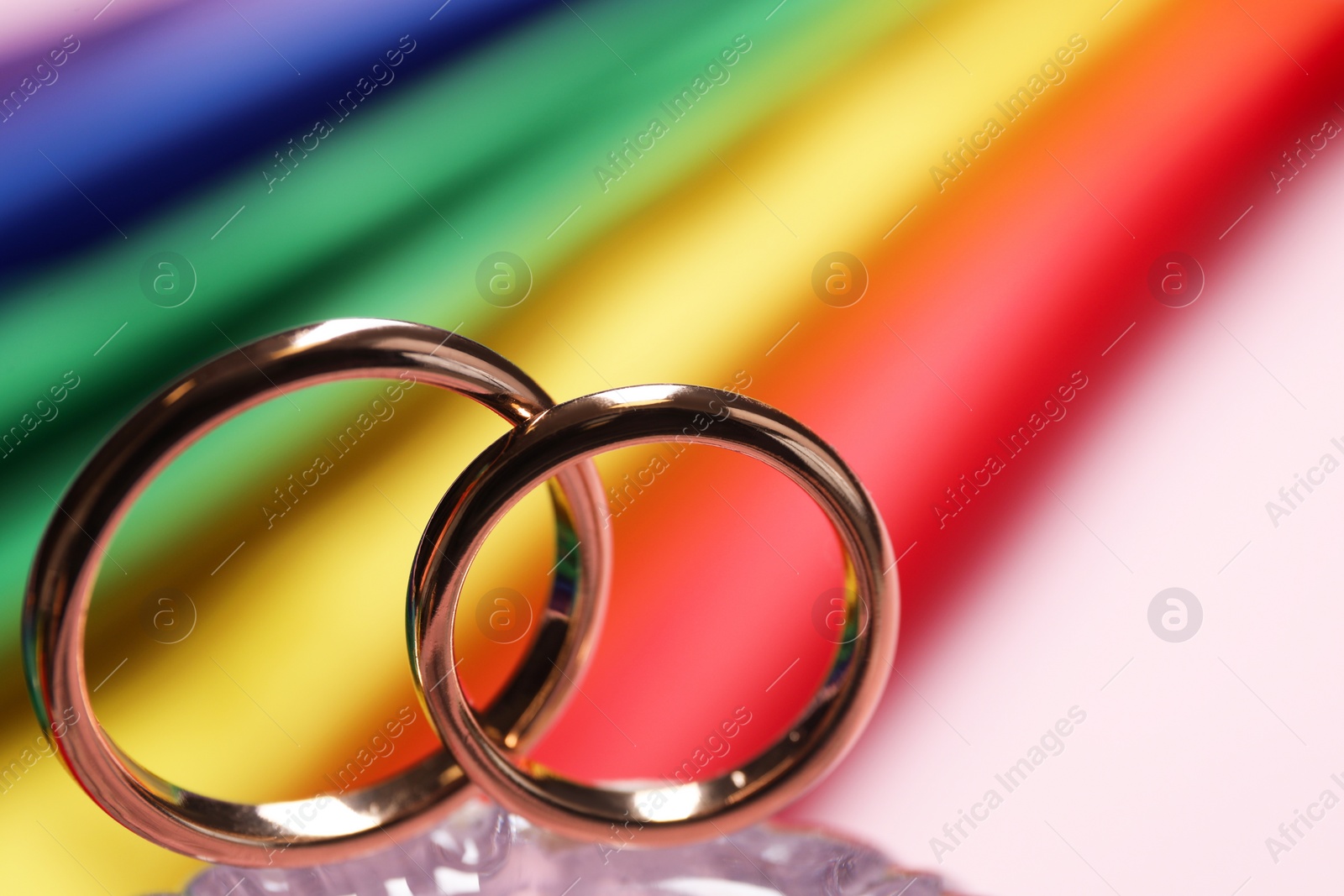 Photo of Wedding rings against rainbow LGBT flag, selective focus