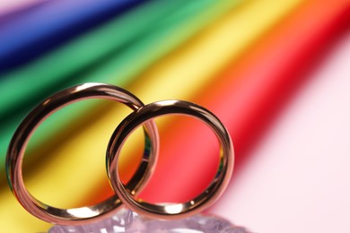 Wedding rings against rainbow LGBT flag, selective focus