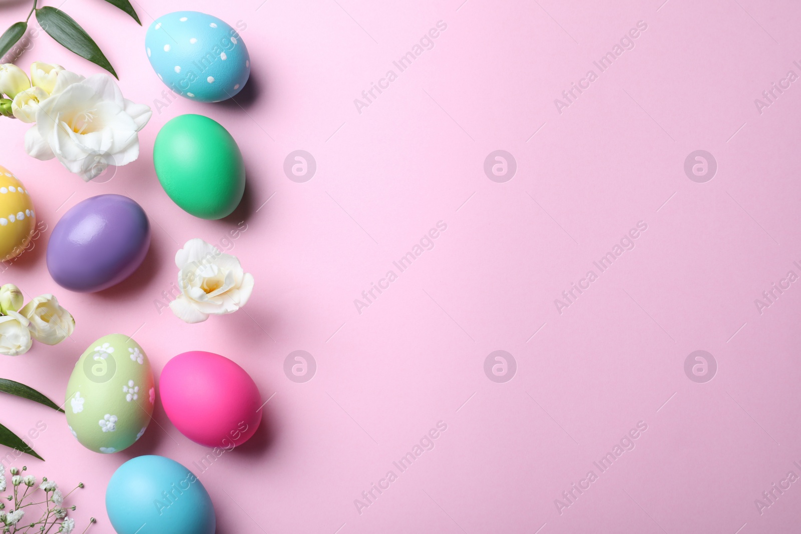 Photo of Bright painted eggs and flowers on pink background, flat lay with space for text. Happy Easter