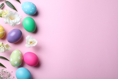 Photo of Bright painted eggs and flowers on pink background, flat lay with space for text. Happy Easter