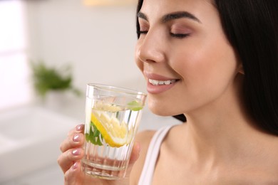 Photo of Young woman with glass of fresh lemonade at home, closeup