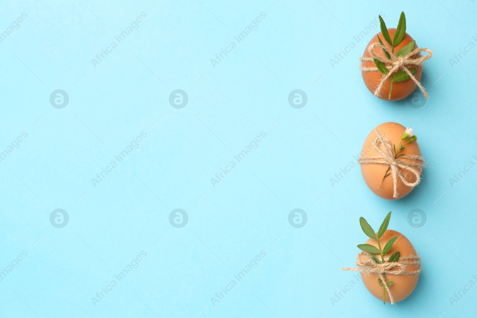 Photo of Festively decorated chicken eggs on light blue background, flat lay with space for text. Happy Easter