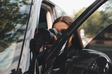 Photo of Private detective with camera spying near car outdoors