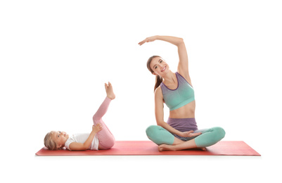 Photo of Young woman and her daughter doing exercise isolated on white. Home fitness