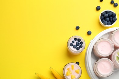 Photo of Tasty yogurt in glass jars and ingredients on yellow background, flat lay. Space for text