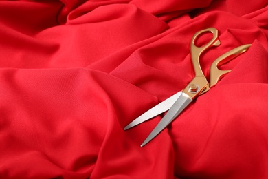 Sharp scissors on red fabric, space for text. Tailoring accessory
