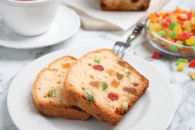 Photo of Delicious cake with candied fruits and tea on table, closeup
