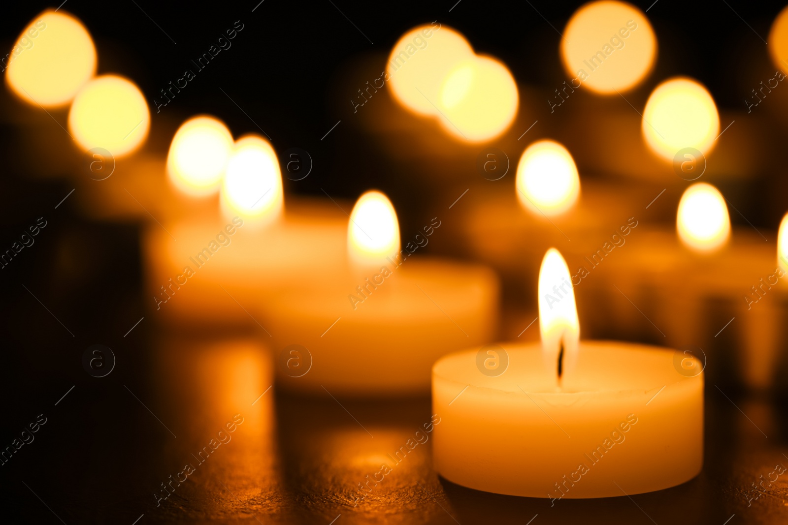 Photo of Burning candles on table, closeup. Funeral symbol