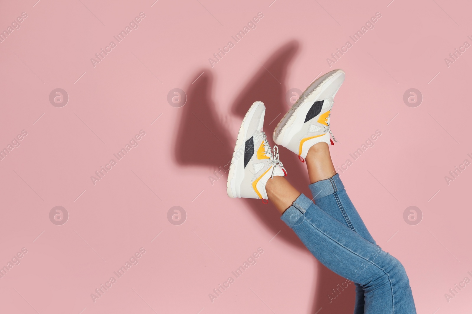 Photo of Woman in stylish sneakers near color wall, closeup. Space for text