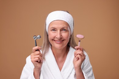 Photo of Woman with metal and rose quartz rollers on brown background. Facial massage