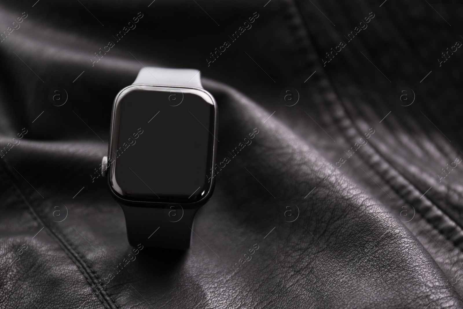 Stylish smart watch on black leather fabric, closeup. Space for text Photo of Stylish smart watch on black leather fabric, closeup. Space for text