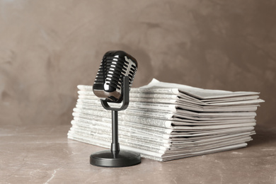 Newspapers and vintage microphone on marble table. Journalist's work