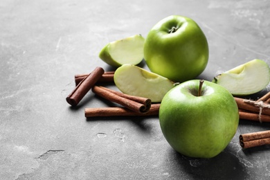 Photo of Fresh apples and cinnamon sticks on gray table