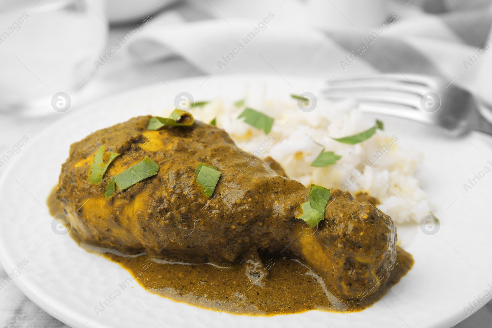 Photo of Delicious rice and chicken with curry sauce served on plate, closeup