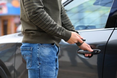 Closeup view of man opening car door with remote key