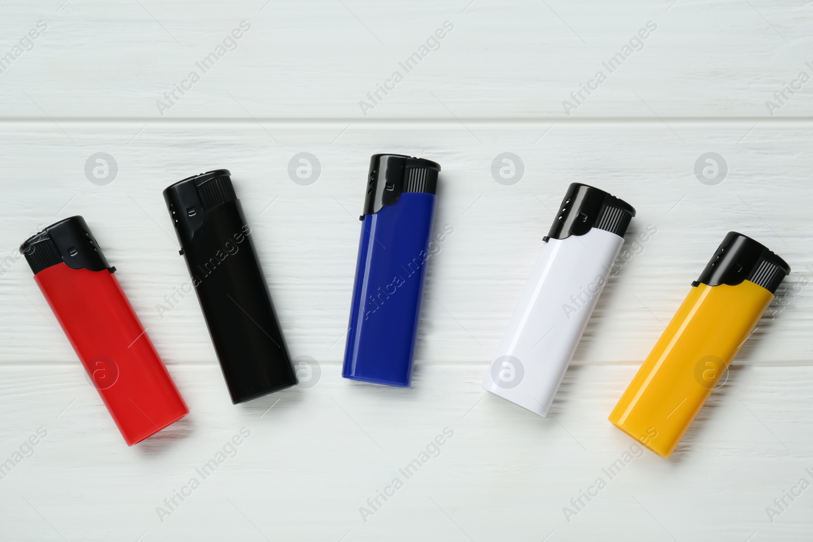 Photo of Stylish small pocket lighters on white wooden background, flat lay