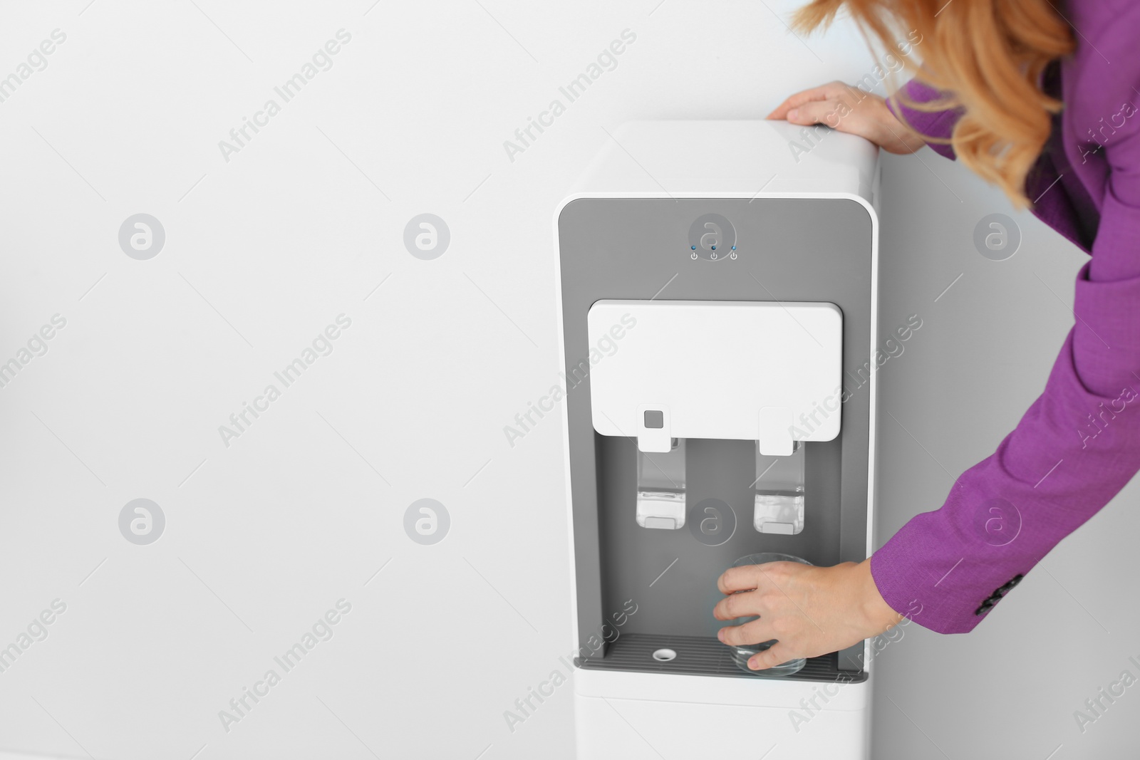 Photo of Woman filling glass from water cooler on white background, closeup. Space for text