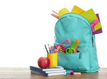 Photo of Stylish backpack with different school stationary and apple on wooden table against white background