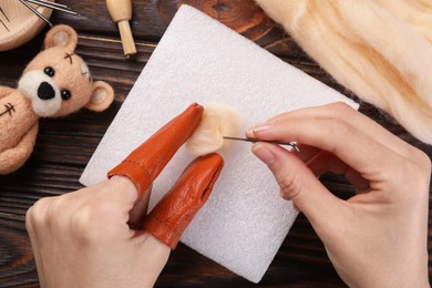 Woman felting from wool at wooden table, top view