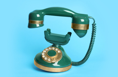 Photo of Green vintage corded phone on light blue background