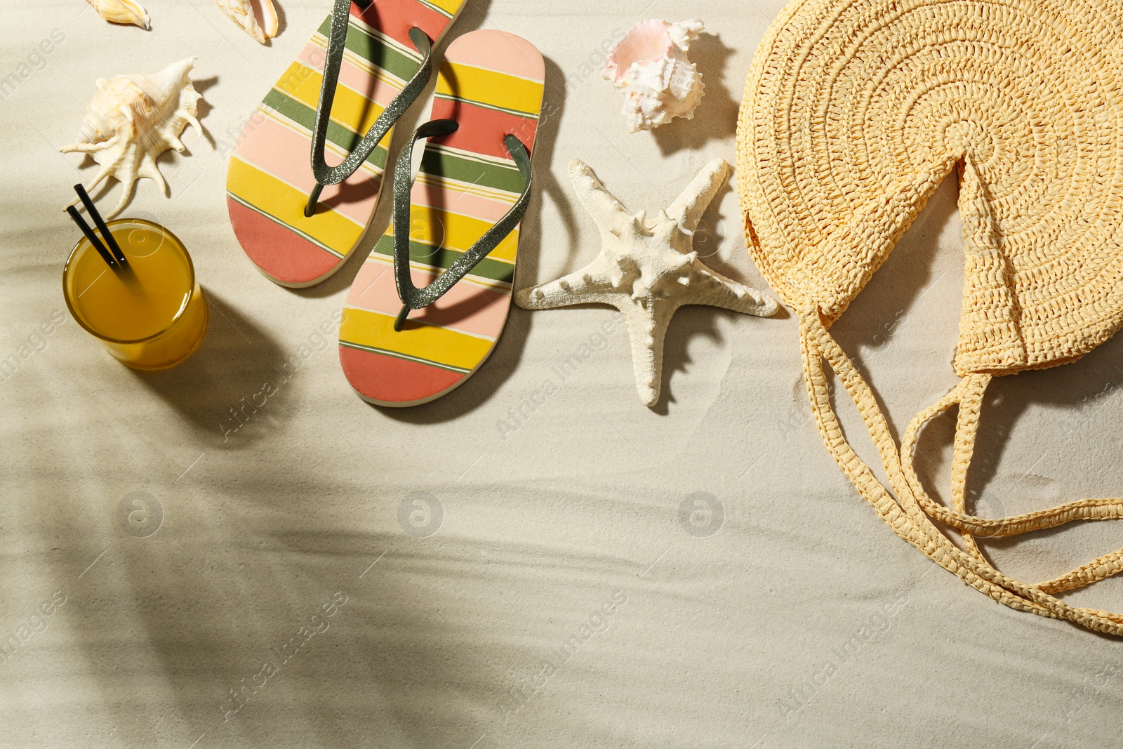 Photo of Different beach accessories and glass of cocktail on sand, flat lay. Space for text