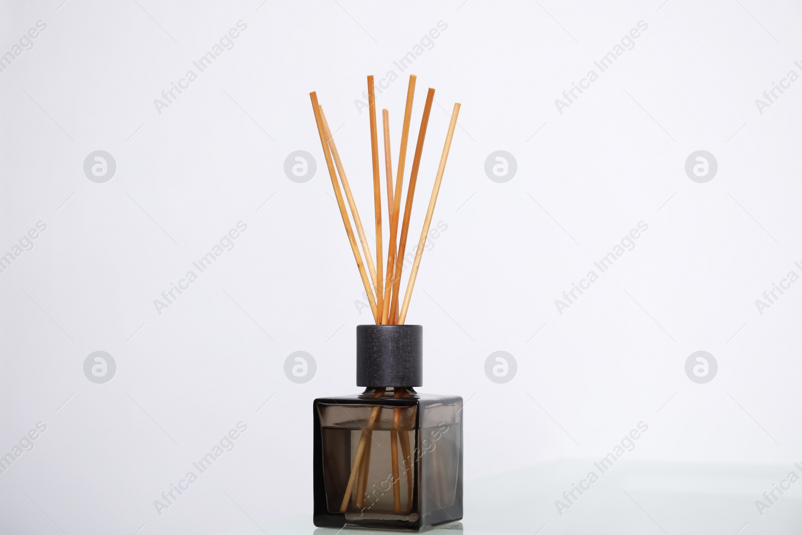 Photo of Aromatic reed freshener on table near white wall