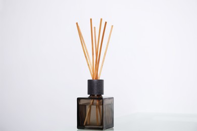 Aromatic reed freshener on table near white wall