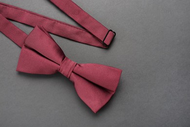 Photo of Stylish burgundy bow tie on dark background, top view. Space for text