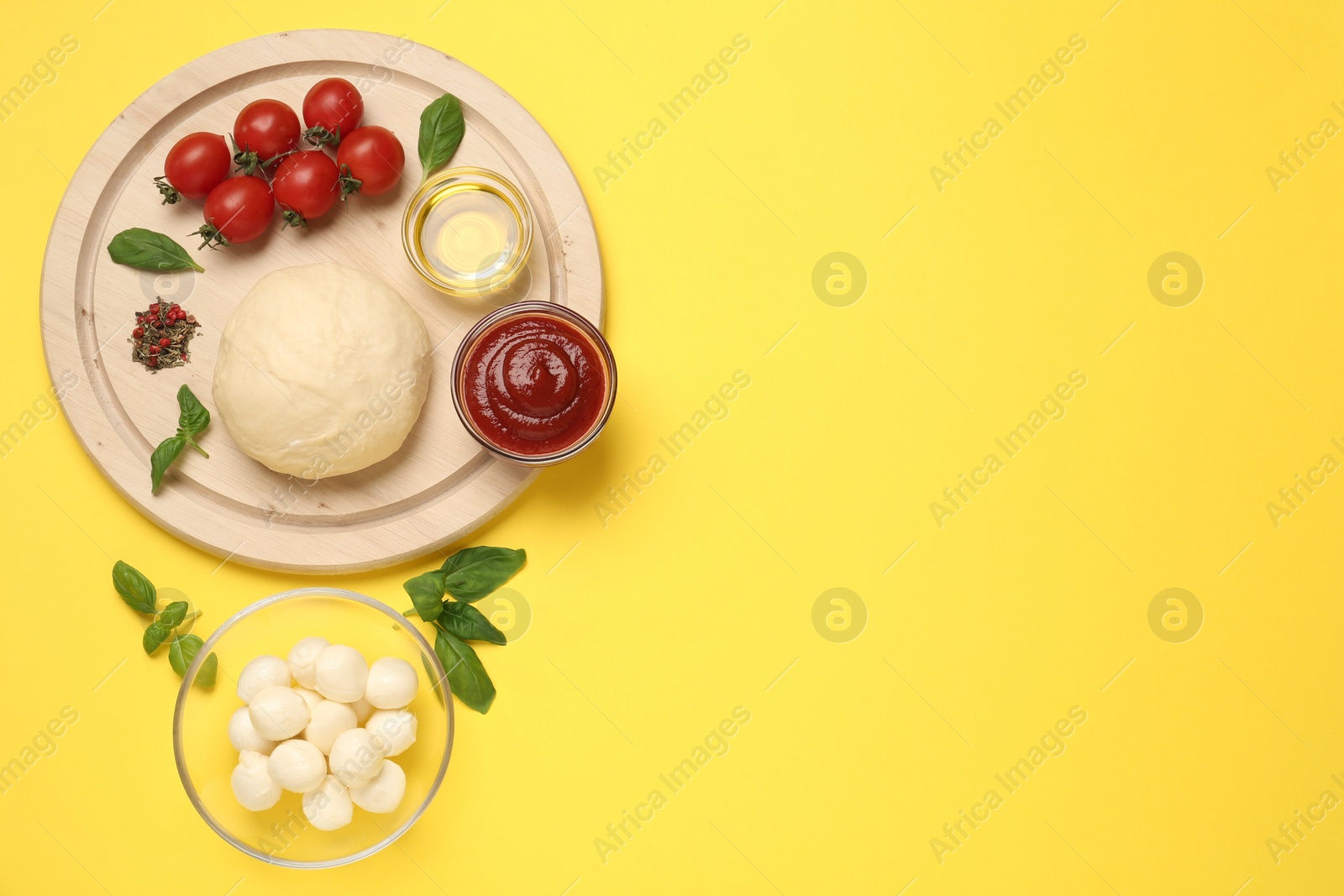 Photo of Raw dough and other pizza ingredients on yellow background, flat lay. Space for text