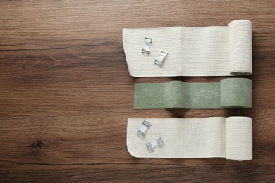 Photo of Medical bandage rolls on wooden background, flat lay. Space for text