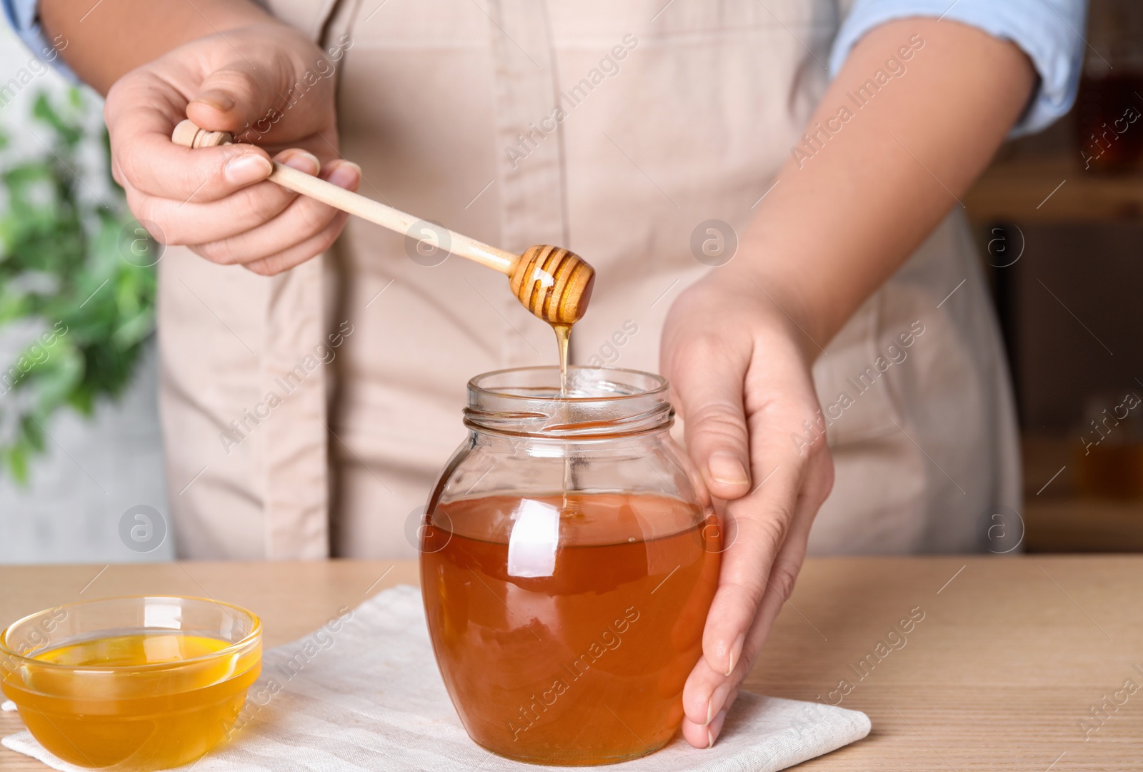 Photo of Woman with tasty honey at wooden table, closeup