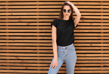 Young woman wearing black t-shirt against wooden wall on street. Urban style