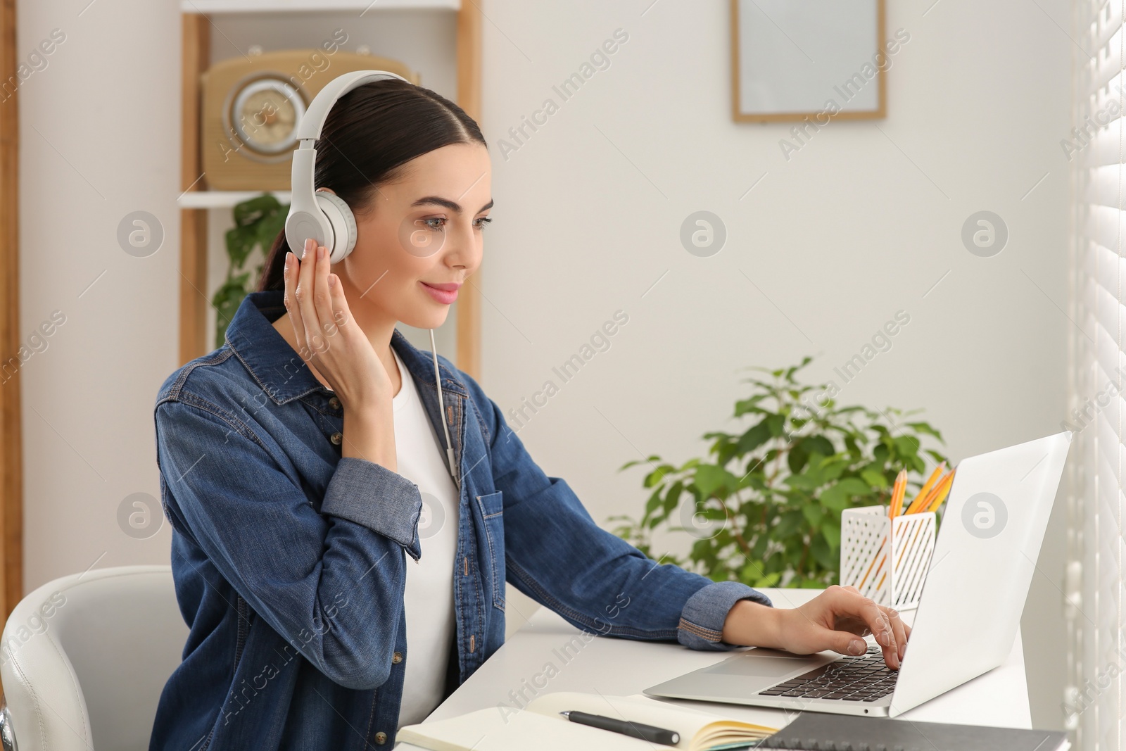 Photo of Woman in headphones studying on laptop at home. Online translation course