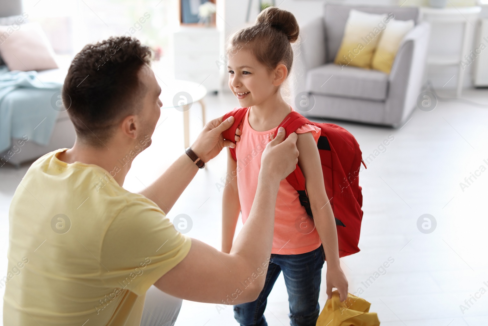 Photo of Young man helping his little child get ready for school at home