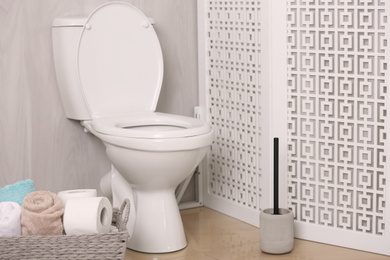White toilet bowl near folding screen in bathroom