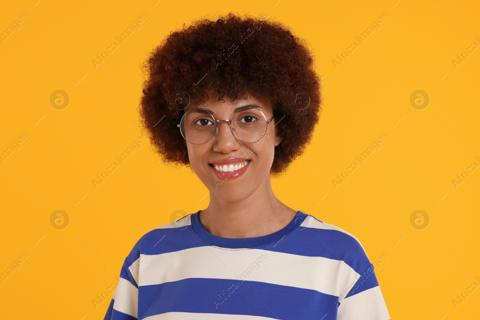 Photo of Portrait of happy young woman in eyeglasses on orange background