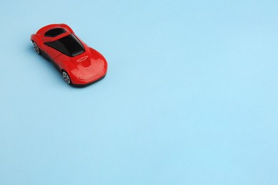 One red car on light blue background, space for text. Children`s toy