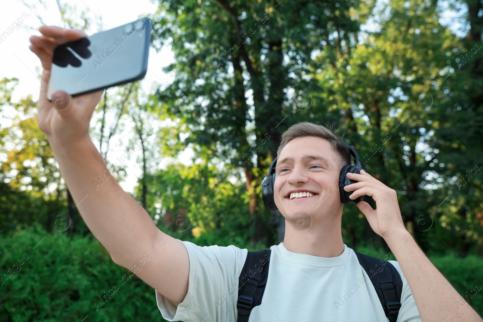 Photo of Smiling man in headphones taking selfie in park