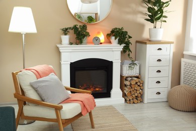 Photo of Stylish fireplace near comfortable armchair in cosy living room. Interior design