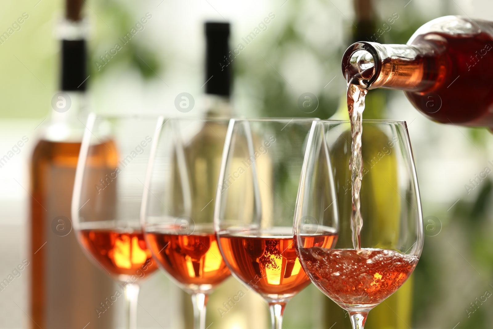 Photo of Pouring white wine from bottle into glass on blurred background, closeup