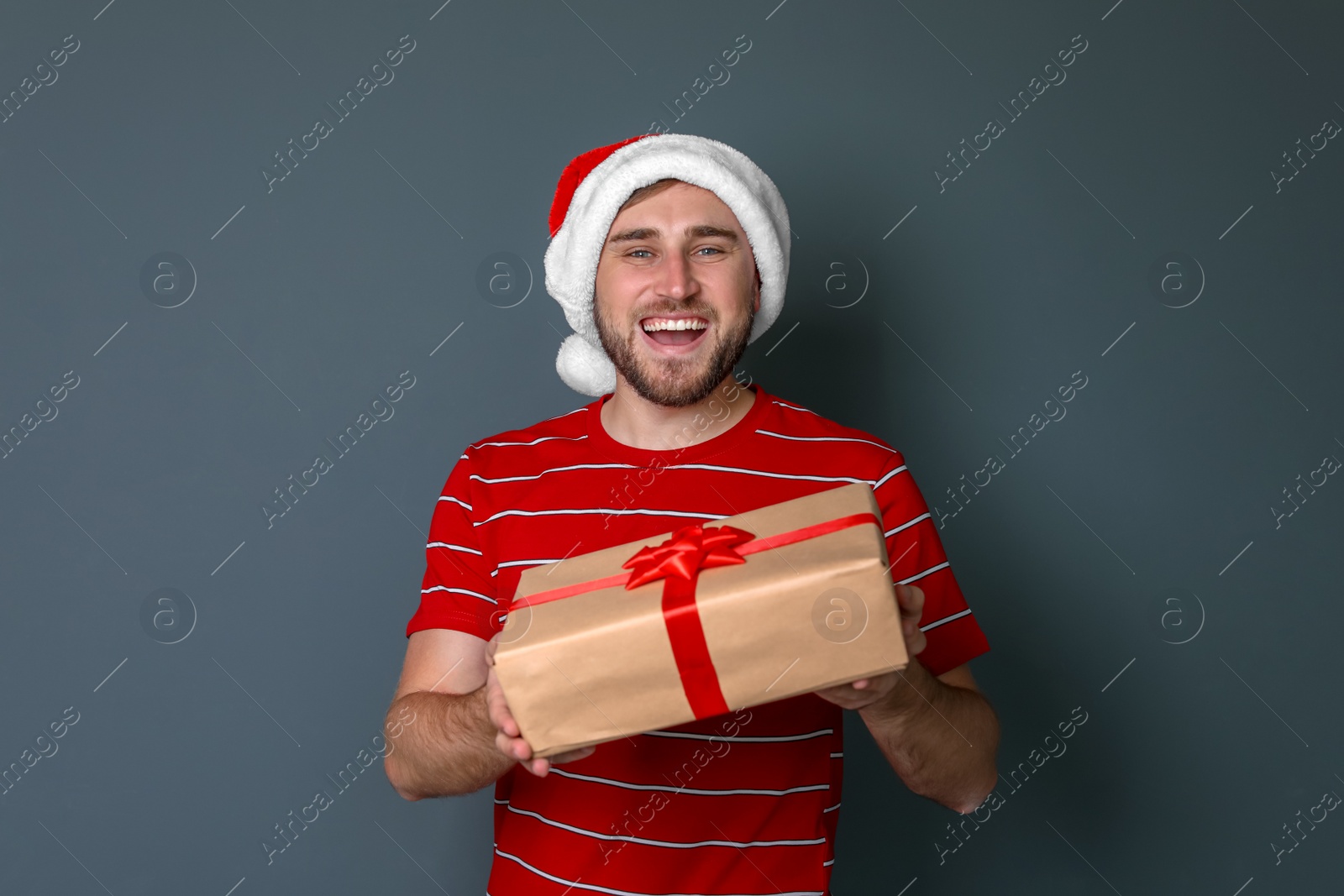 Photo of Young man with Christmas gift on grey background